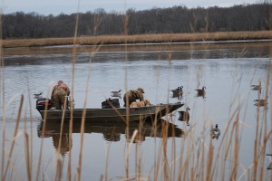 Two men hunting waterfowl on a small motorboat