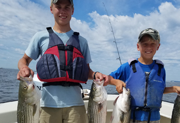 Photo of: Boys on boat with striped bass