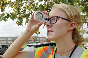 Photo of: Woman measuring tree with device held to her eye