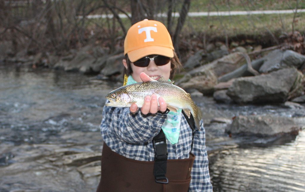 Photo of: Boy near river holding trout