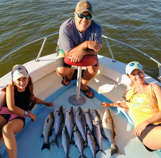 Photo of family on boat with striped bass