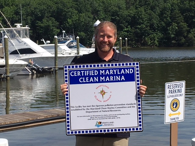 Photo of man holding Clean Marinas certification at marina