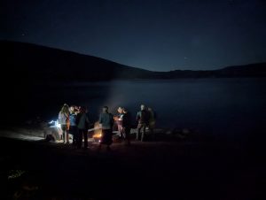 A group gathered around a camp fire by Lake Habeeb