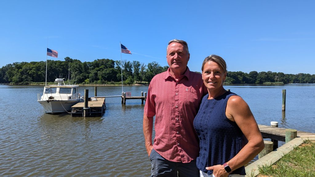 A photo of two people in front of a body of water.