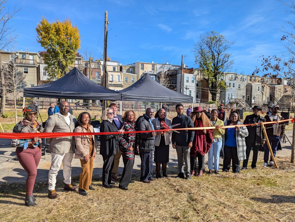 A ribbon cutting in a green area, with a row of houses in the background.