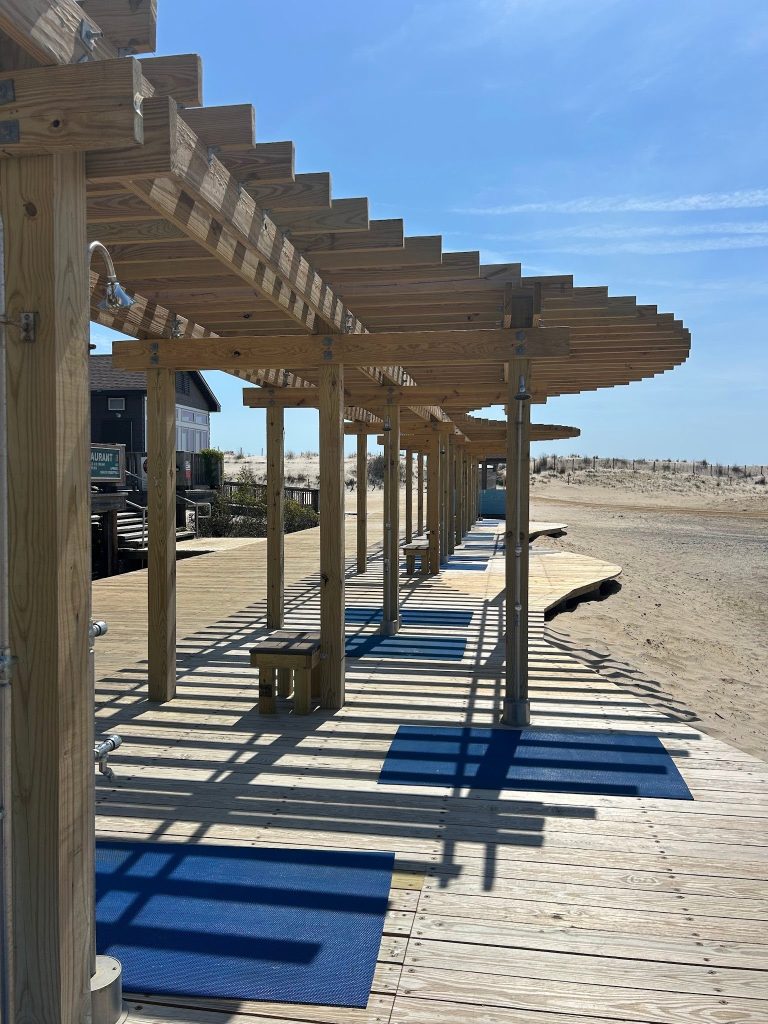 A line of showers along a wooden boardwalk.