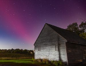aurora behind a barn on a dark night