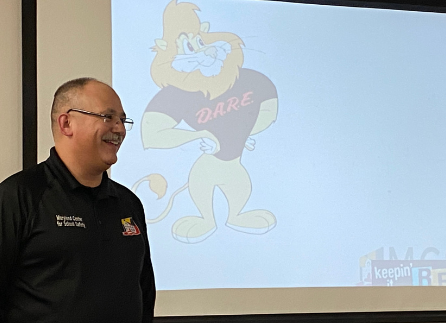 James Hott stands in front of the DARE logo as he presents.