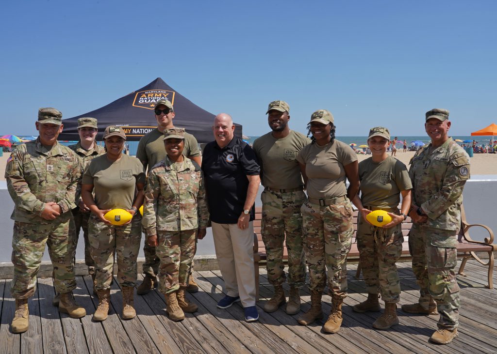 Maryland Governor Larry Hogan poses for a photo with leadership of the Maryland Army National Guard and Soldiers with Recruiting and Retention Battalion, near the boardwalk at 7th Street in Ocean City, Maryland, August 18, 2022. The MDARNG hosted their annual “summer surge” recruiting events during the busy vacation season and the Maryland Association of Counties conference. (U.S. Air National Guard photo by Capt. Benjamin Hughes)