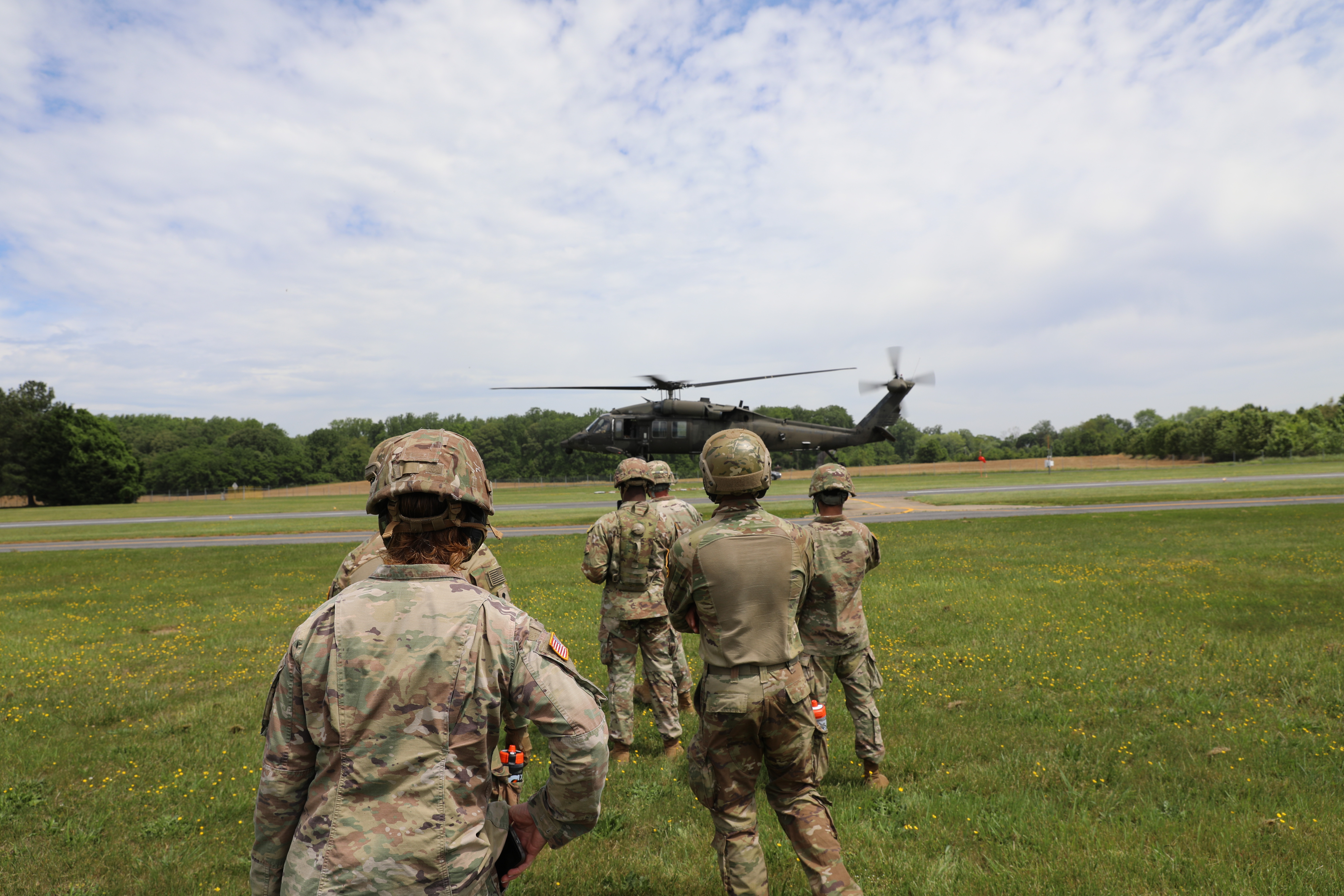 Soldiers watch from afar as a helicopter lands