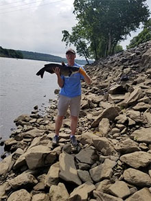 Photo of man on a bank holding a catfish - Photo courtesy of Jim Summers 