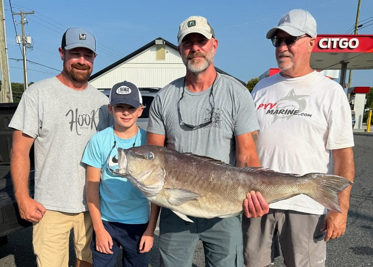 Photo of four people holding a fish on a dock