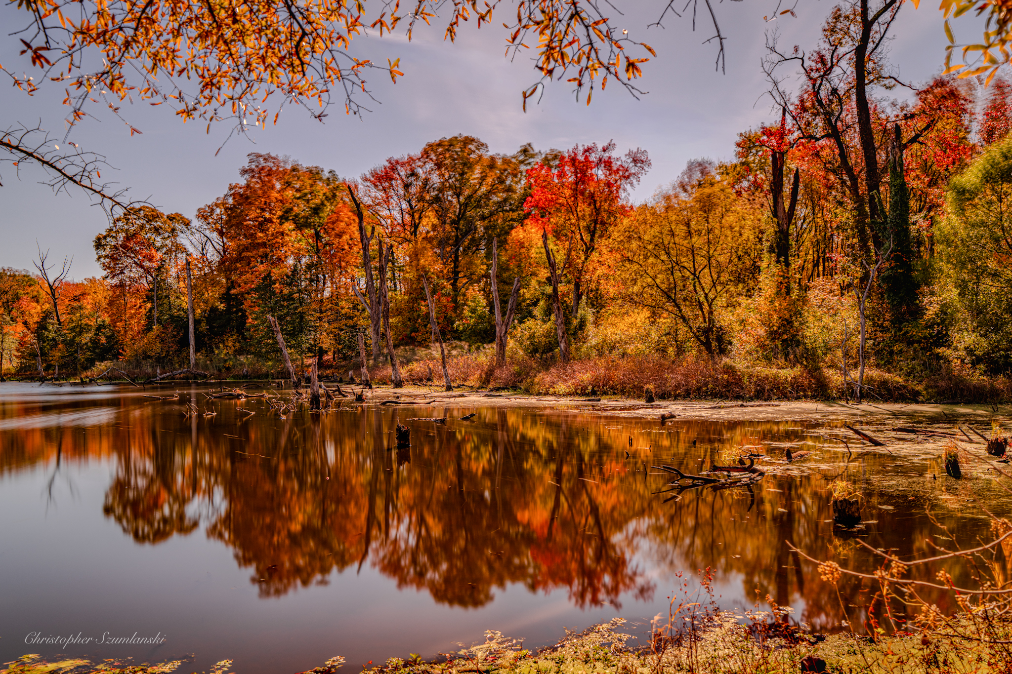 Oranges, reds and yellow of fall foliage reflected in the water at North Point State Park.