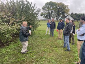 Man demonstrating trees to a group of people in a large garden