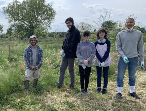 Agro-Forester Francis Smith, left, demonstrates tick safety with hard boots, long sleeves, long pants, and work gloves at White Marsh Park in Centreville in 2023. On the right, a student demonstrates the sock-tucking strategy for tick prevention. 