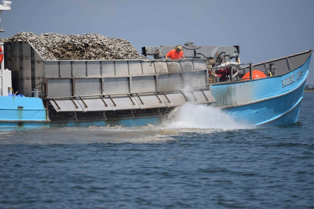 A boat releasing oyster shells into the water